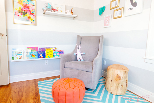 Modern Glider with Coral Pouf in this Reading Nook